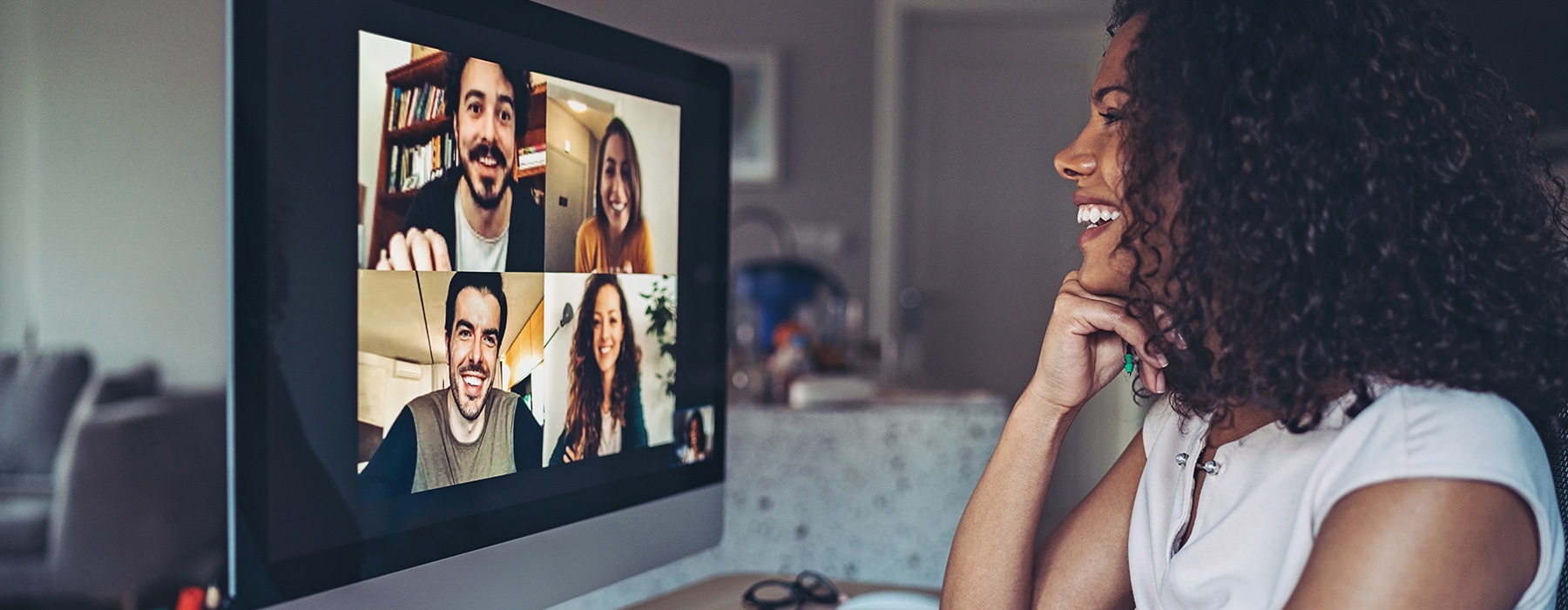 lifestyle image of a woman talking to people on a comupter through a zoom or meeting call online